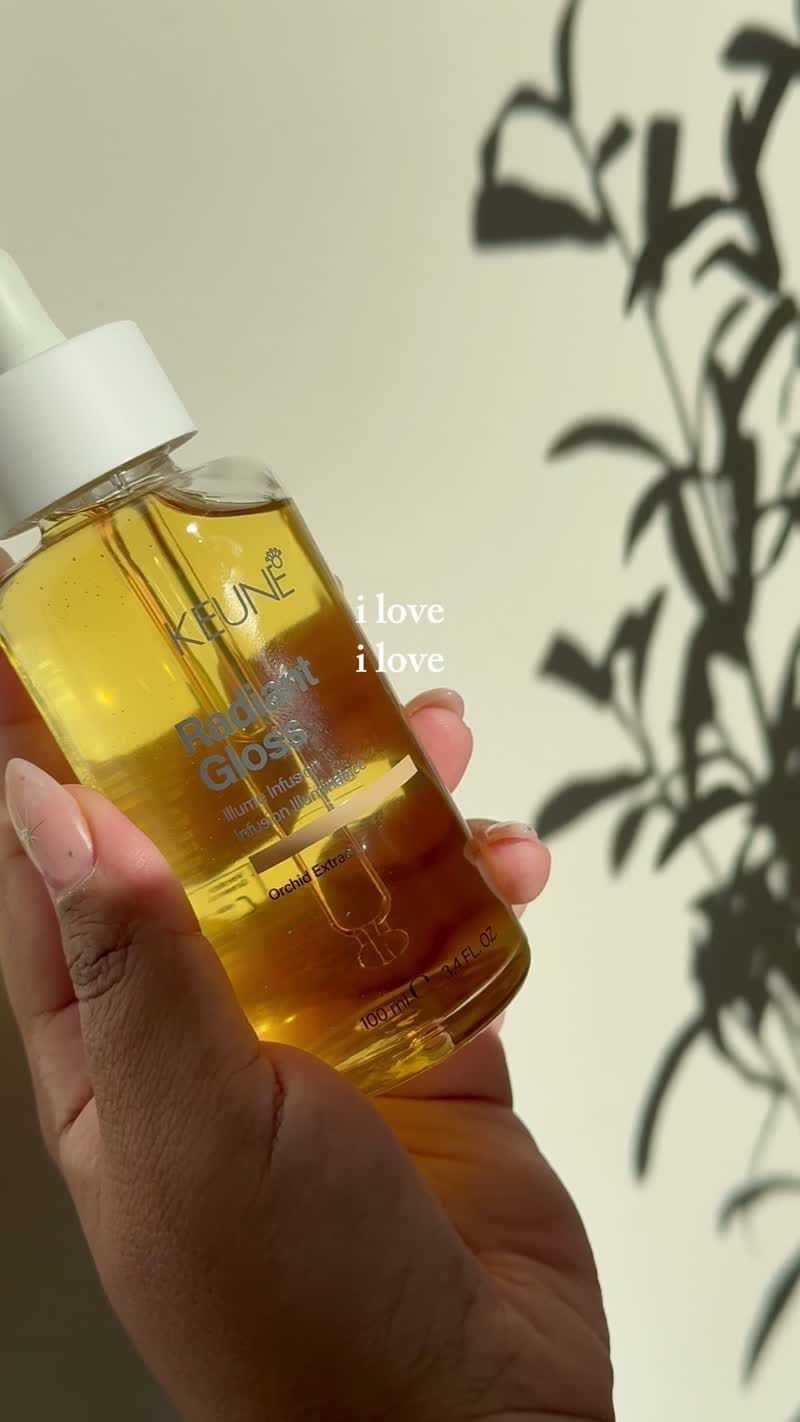 KLUVI Radiant Glow serum bottle held against leafy shadow on wall.