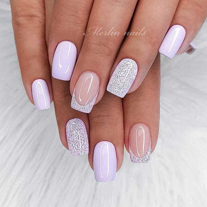 Pastel purple nails with glitter accents on a white fur background.