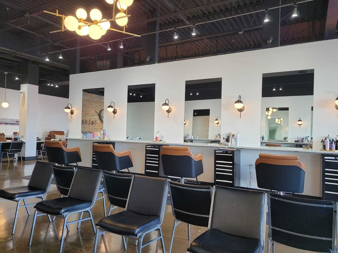 Modern hair salon with stylish decor, multiple mirrors, and numerous haircutting stations.