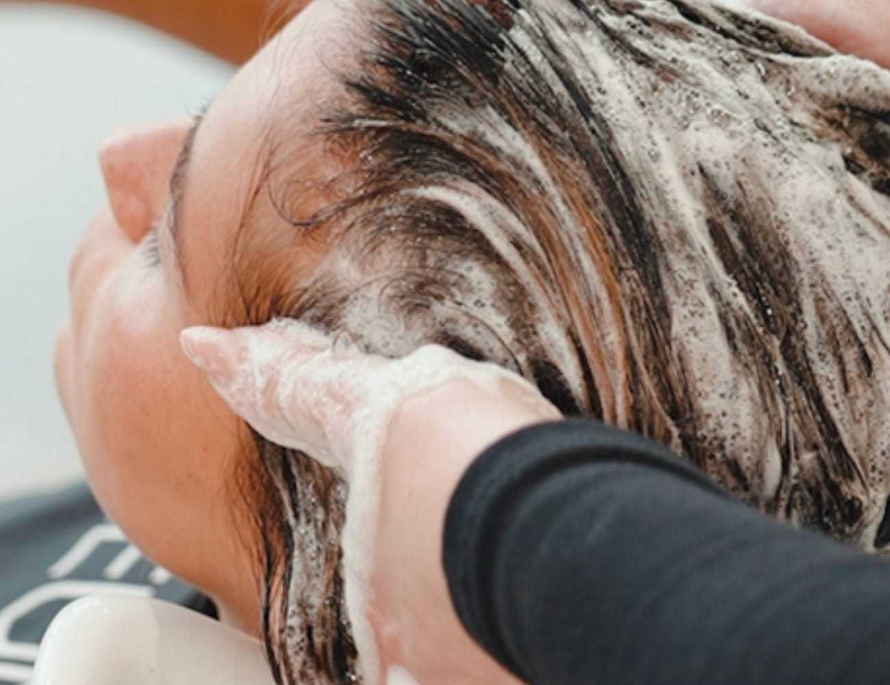 Person receiving a relaxing shampoo hair wash at a salon.